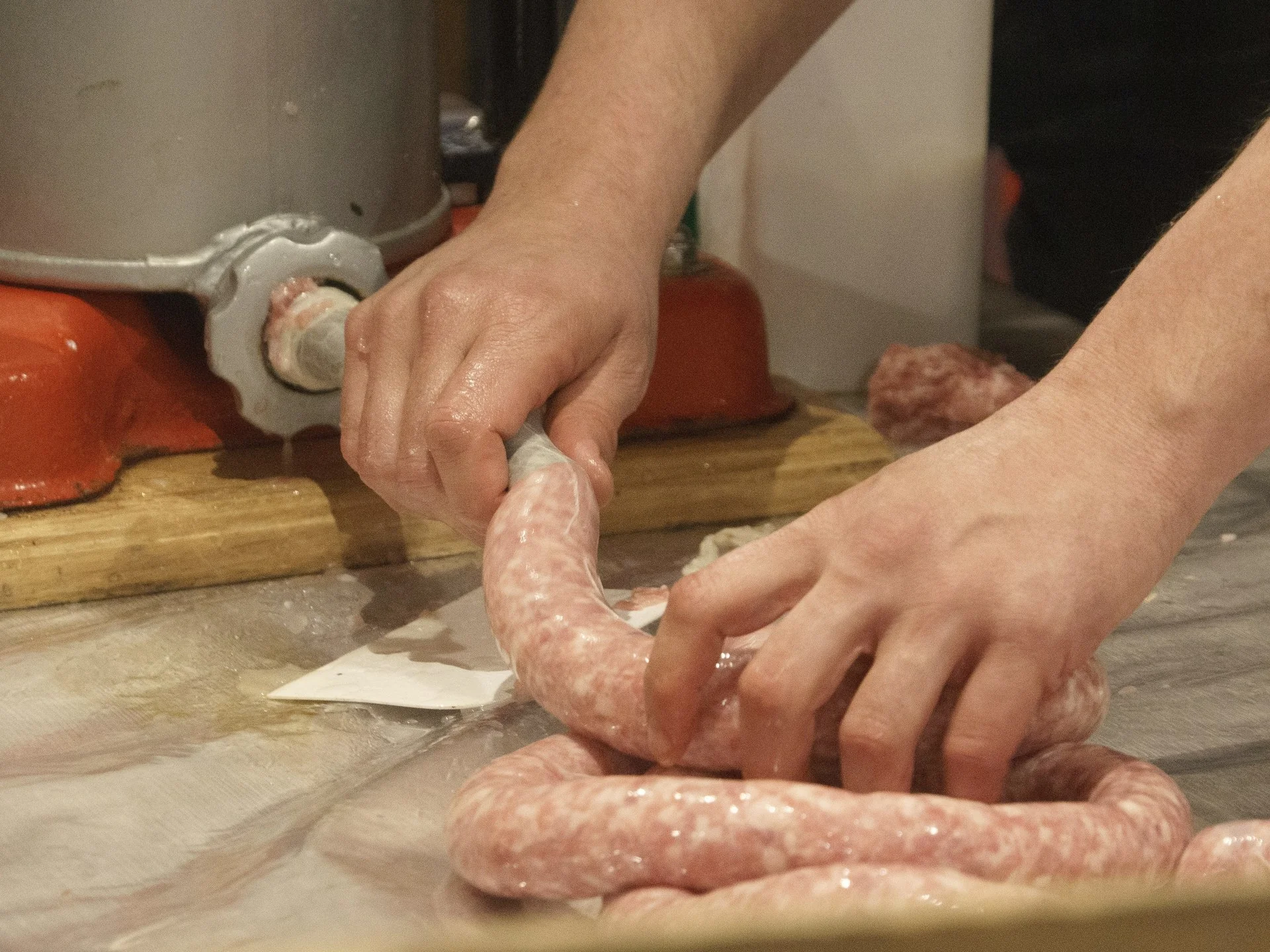 Des mains façonnent des saucisses sur le plan de travail.