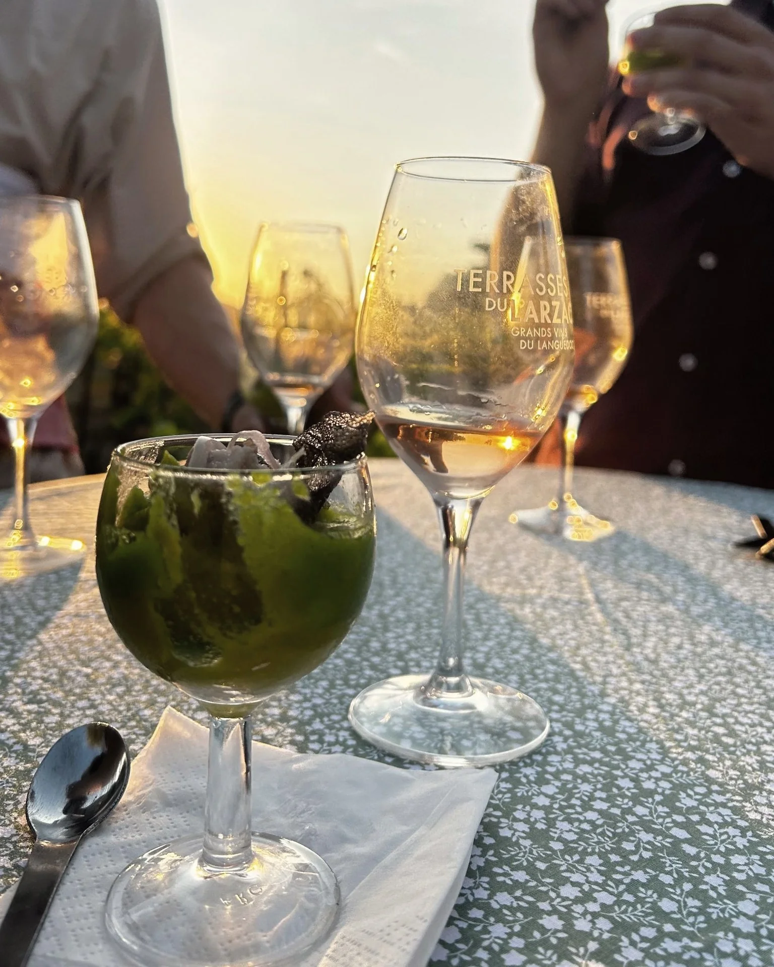 Verres de vin et verrine sur une table en terrasse, au coucher du soleil.